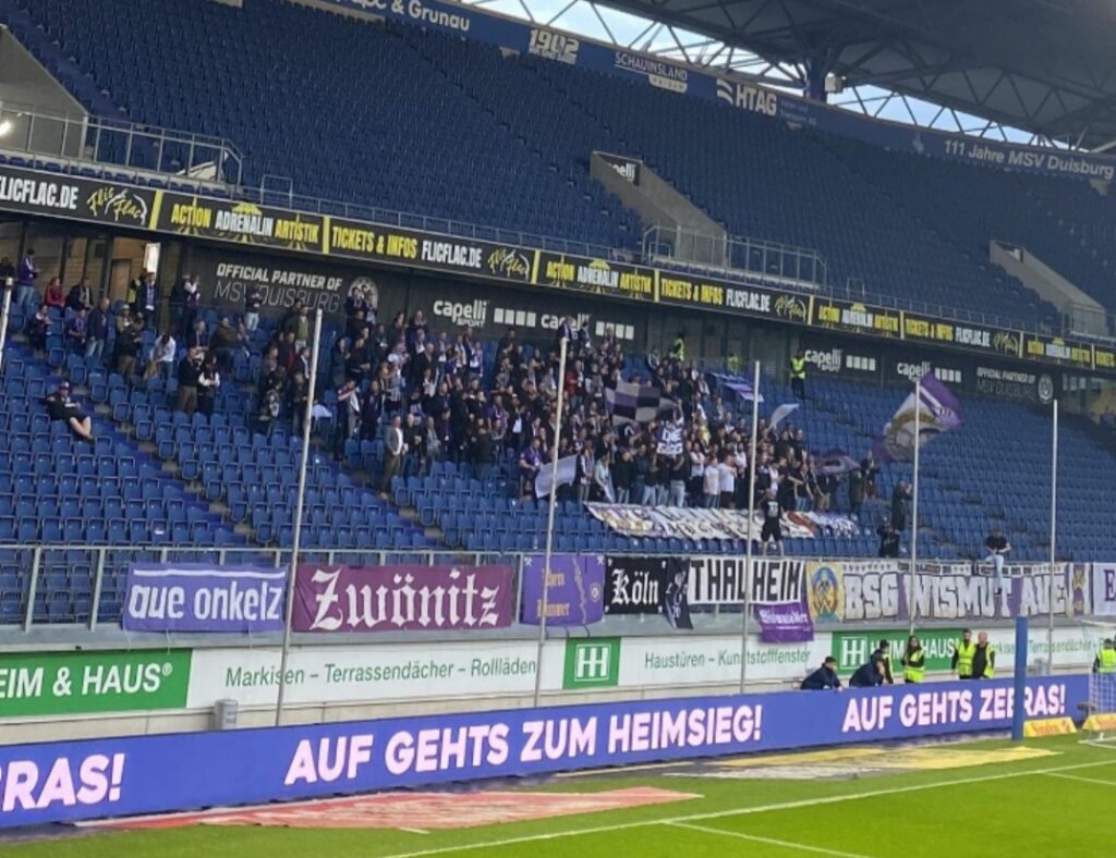 Foto des spärlich gefüllten Gästeblocks mit den Fans des FC Erzgebirge Aue im Wedaustadion.
