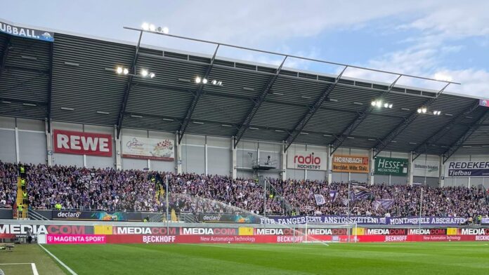 Der Gästeblock mit den Fans des VfL Osnabrück, welche ein Spruchband zeigen, auf welchem "Für fangerechte Anstoßzeiten: Montagsspiele abschaffen"