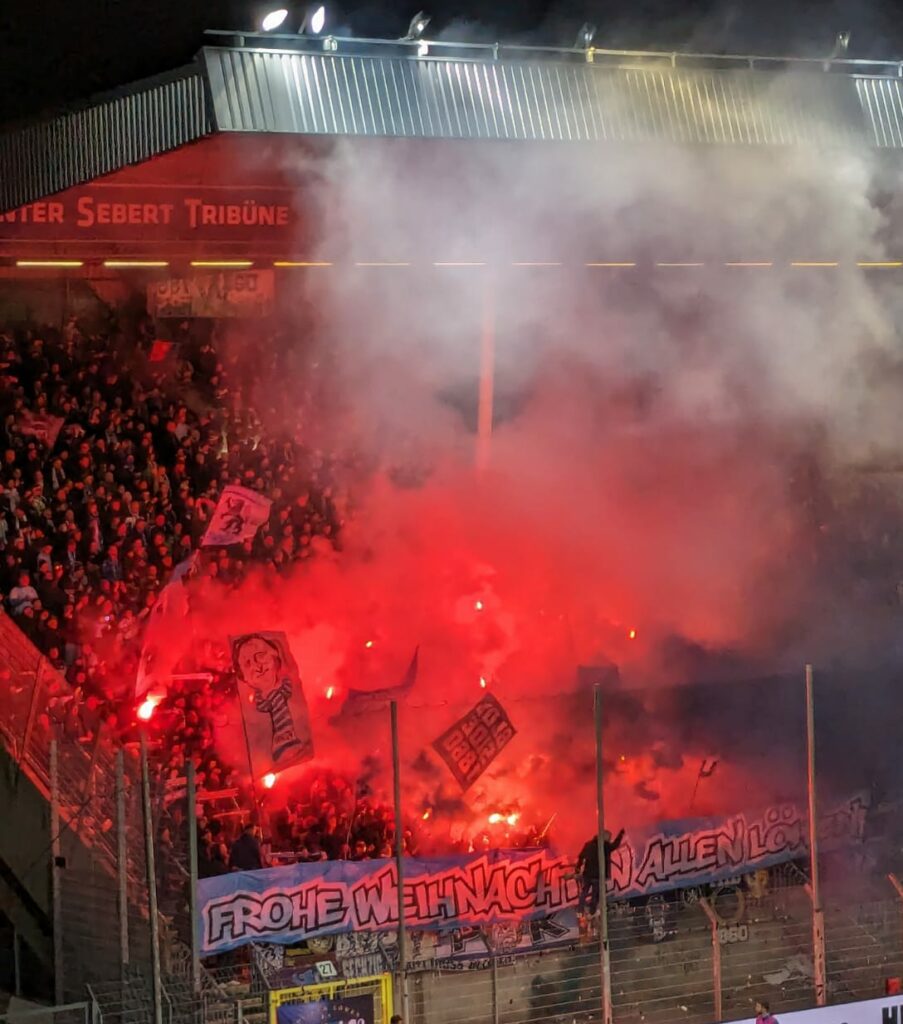Die Ultras von 1860 wünschen allen Löwenfans ein frohes Weihnachtsfest mit einem gemalten Banner sowie einer Begleitung durch einige Bengalos.